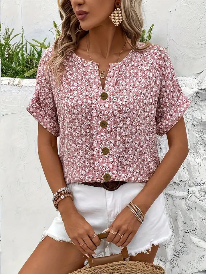 Damen Sommer Top flach liegend, zeigt den lebhaften Blumenprint, kurze Ärmel und die Knopfleiste. Feminin.
