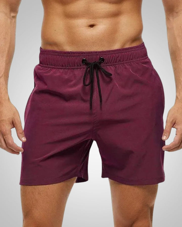 Entspannter Mann am Pool trägt schnelltrocknende, bequeme Herren Badeshorts für den Sommerurlaub.
