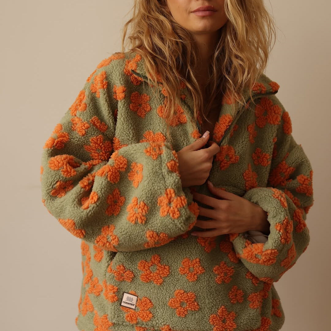 Nahaufnahme des farbenfrohen Blumenmusters auf dem Herbst-Damenpullover. Gelb, Rosa, Orange Töne.