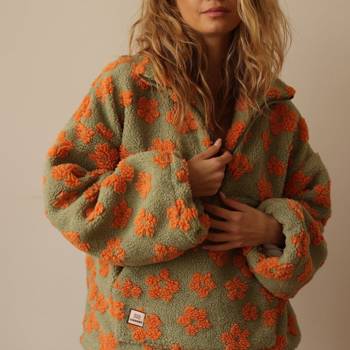 Nahaufnahme des farbenfrohen Blumenmusters auf dem Herbst-Damenpullover. Gelb, Rosa, Orange Töne.
