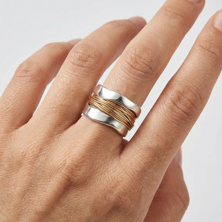 Edler Damen Silberring mit goldenen Akzenten. Modernes Wickeldesign, eleganter Fingerschmuck für jeden Look.
