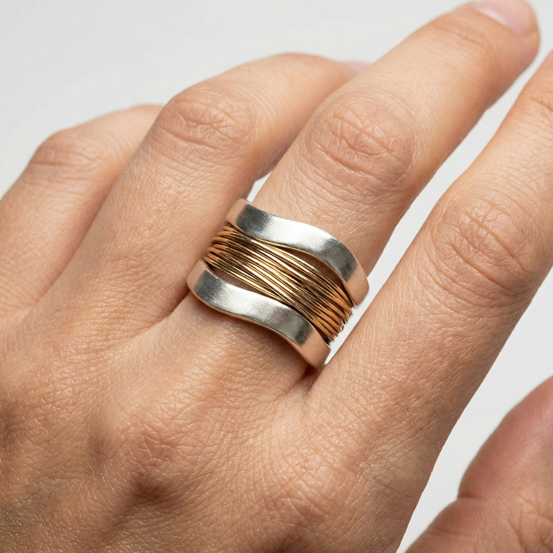 Glänzender Damen Silberring mit goldenen Akzenten, elegantes Wickeldesign. Luxuriöser Schmuck, zeitloses Accessoire.