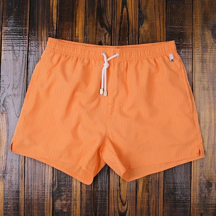 Stofftextur der gestreiften Herren-Badeshorts. Atmungsaktive Bademode für heiße Tage.