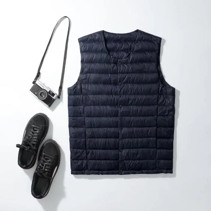 Mann trägt ärmellose, ultraleichte Daunenweste. Warm, packbar & ideal für Schichtlooks im Herbst/Winter.