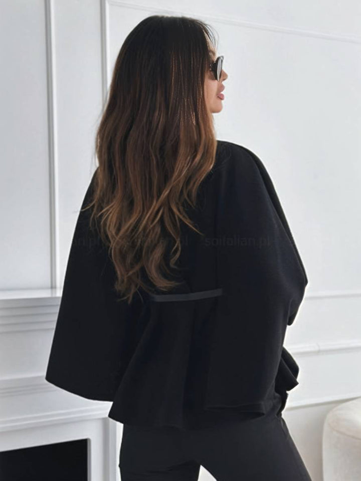 Detailaufnahme: Gürtel & lockere Fledermausärmel einer Damen Ponchojacke im herbstlichen Stil.
