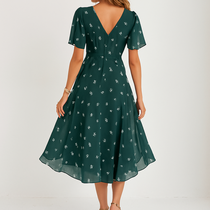 Frau trägt elegantes rosa Blumen Midi-Sommerkleid mit V-Ausschnitt & Schmetterlingsärmeln, ideal für Freizeit.