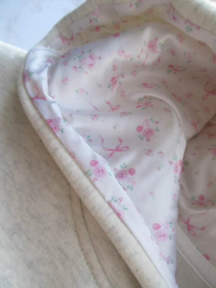 Eleganter Elfenbein Damen Kapuzenpullover mit lockerer Passform und femininen rosa Schleifen-Details.