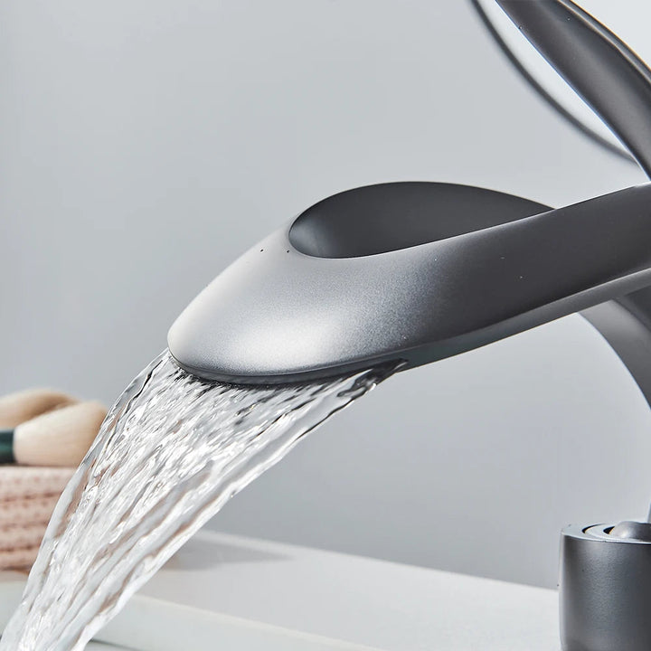 Detailansicht: Moderner Wasserfall-Auslauf einer Messing Waschtischarmatur.