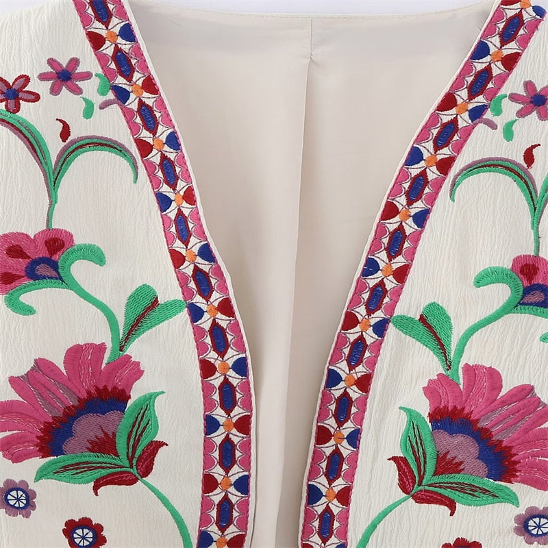 Nahaufnahme einer rosafarbenen Vintage Damen Weste mit blauer Blumenstickerei, perfekt für den Schichtenlook.