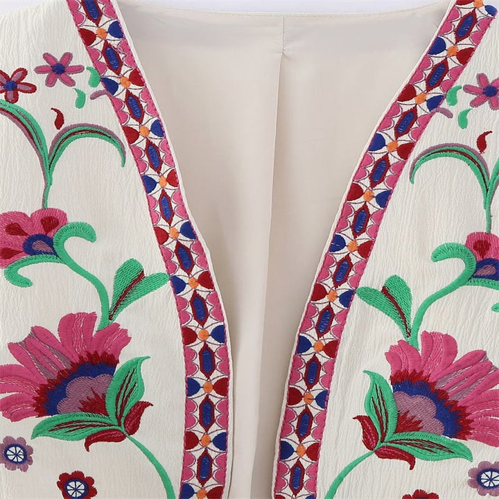 Nahaufnahme einer rosafarbenen Vintage Damen Weste mit blauer Blumenstickerei, perfekt für den Schichtenlook.
