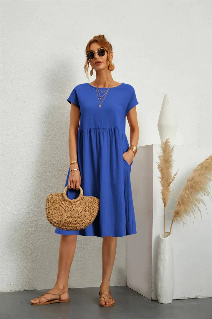 Luftiges blaues Damenkleid mit Rundhals, Kurzarm & seitlichen Taschen, perfekt als Alltags- oder Urlaubskleid.