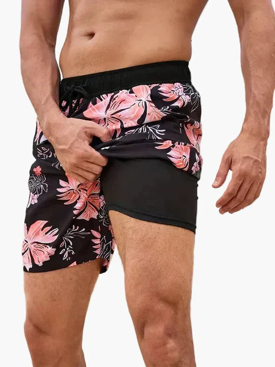 Mann trägt tropische Herren Badeshorts mit Kompression am Strand, bereit zum Schwimmen & Sport.