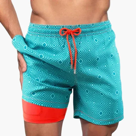 Mann präsentiert sportliche Herren Badeshorts mit tropischem Print & Kompression, ideal für den Sommer.