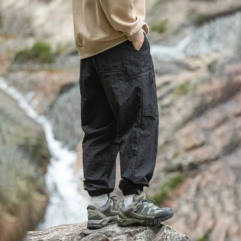 Aktiver Mann trägt wasserfeste Outdoorhose beim Wandern in der Natur, optimale Funktionshose.