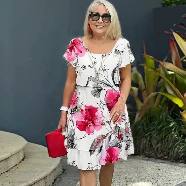 Frau geht in einem fließenden, geblümten Sommerkleid mit Rüschen, perfekt für den Strand.