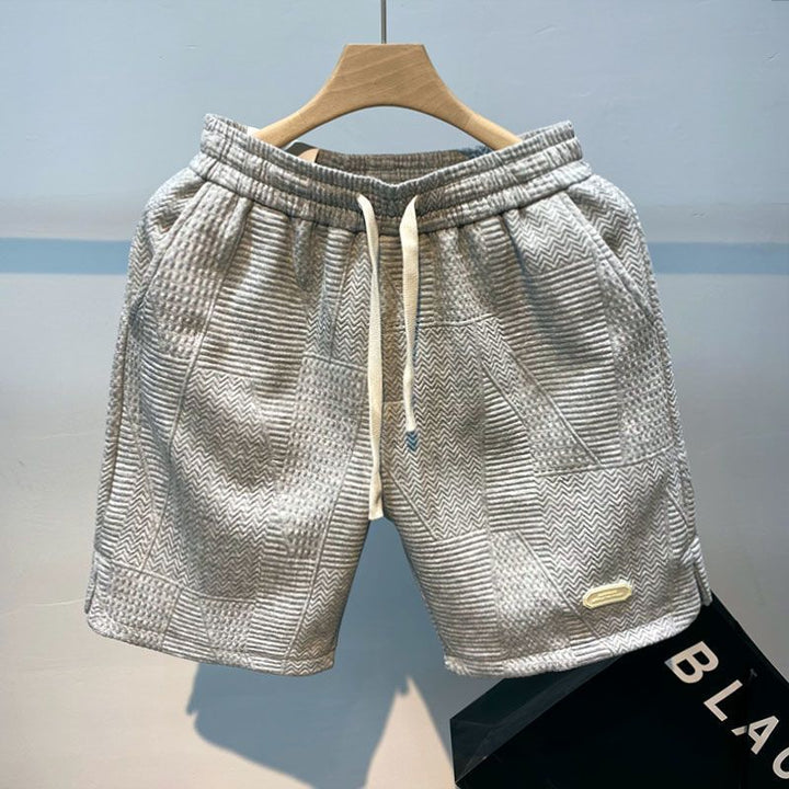 Mann trägt stilvolle Herren Casual Shorts am Strand; ideal als Sommer Shorts für Sport, Freizeit & Strandmode.